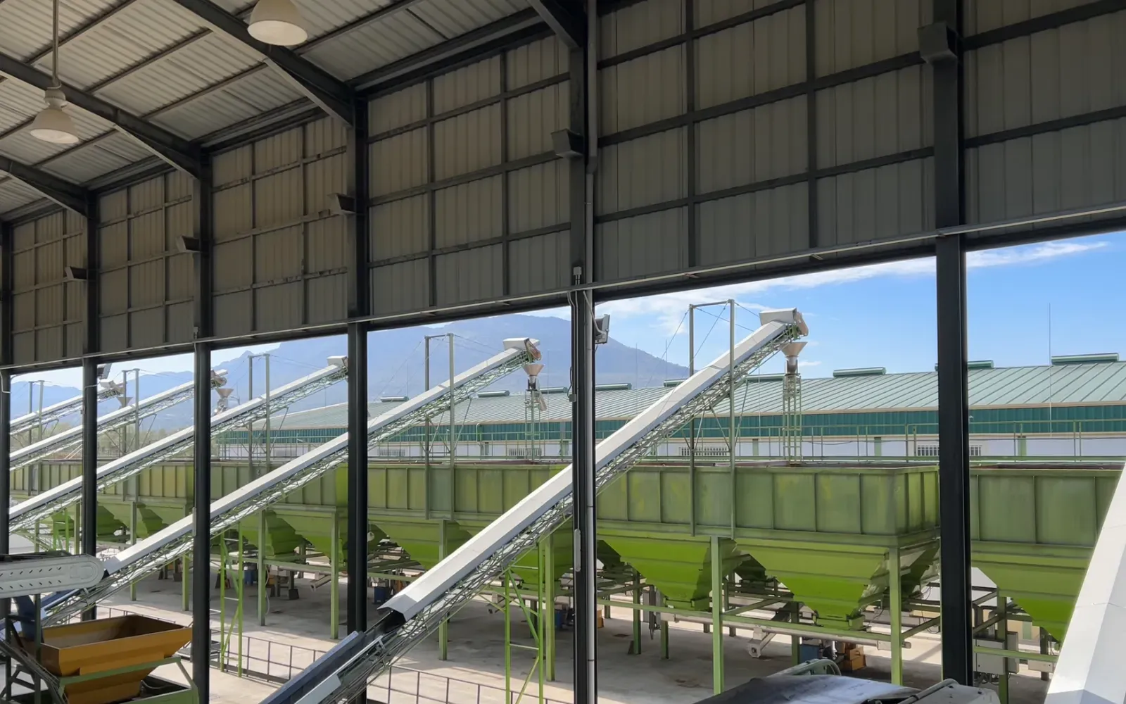 Industrial warehouse with conveyor belts and feed hoppers, viewed from a catwalk